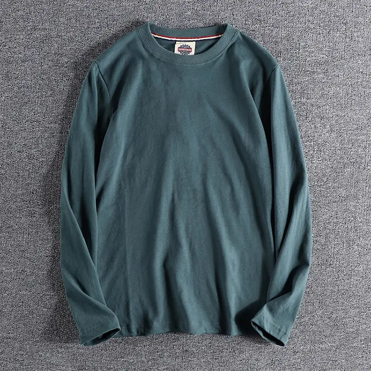 Camiseta tipo jersey de color liso lavado verde azul oscuro de manga larga con un ribete sutil de cuello acanalado y diseño de cuello redondo.