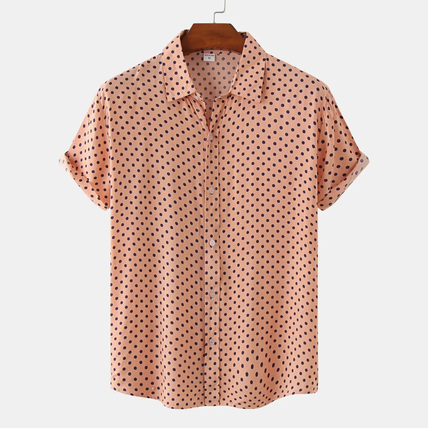 Men plus size peach-colored short-sleeved button-up shirt with dark brown polka dot pattern hanging on a wooden hanger.