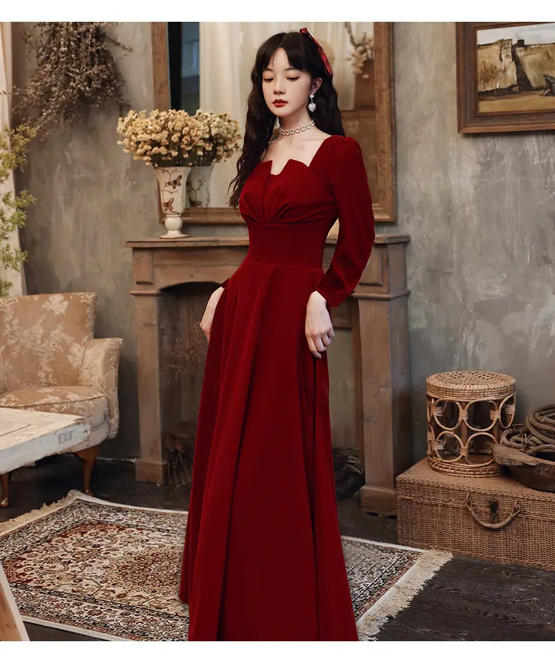 A rich burgundy velvet long sleeve a-line gown featuring a square neckline and fitted bodice.