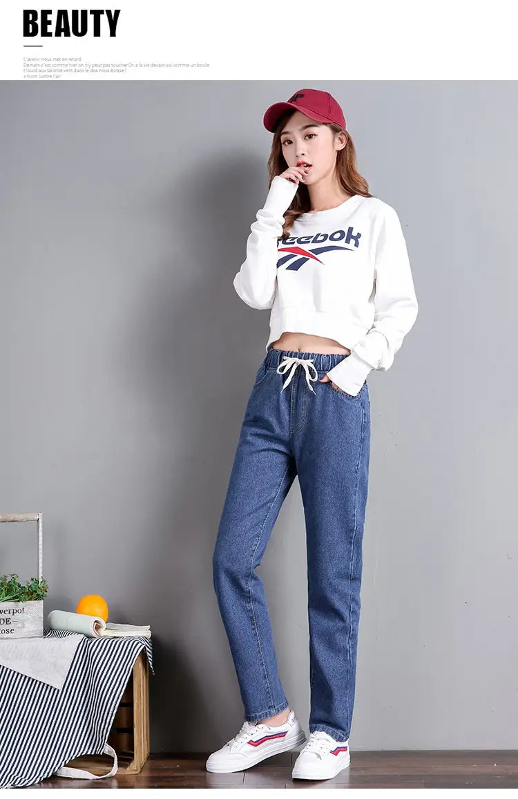sweat-shirt Reebok court blanc avec logo noir et rouge, associé à un jean droit en denim bleu taille haute style coréen