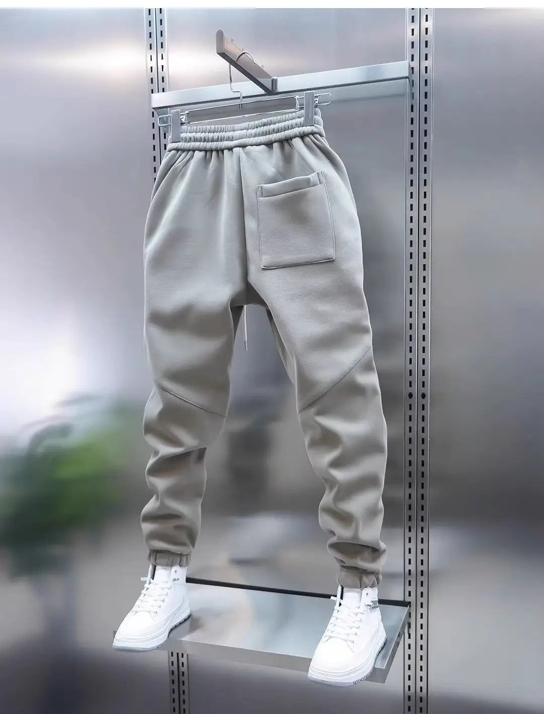 Gray mens casual solid color sweatpants made of soft fabric with an elastic waistband and a single front pocket displayed on a hanger.