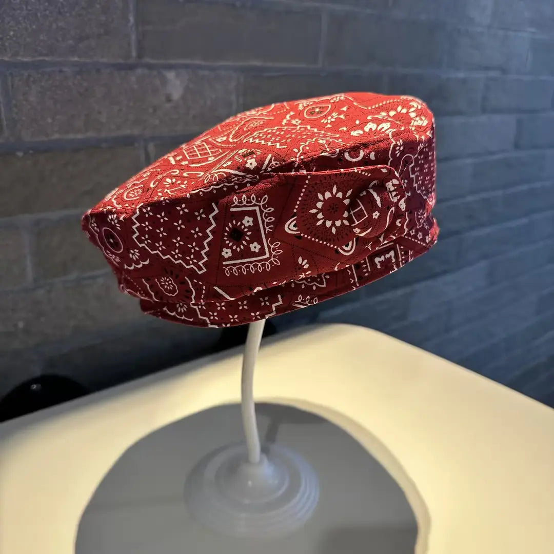 A red bandana-patterned printed Korean style fashion cap made of soft fabric featuring white geometric and floral designs.