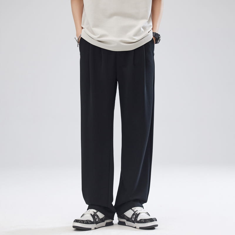Pantalon pour hommes à plis, coupe ample à jambes larges et ajustement décontracté, couleur noir, avec une silhouette à coupe droite et des plis discrets au niveau de la ceinture.