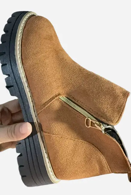 Botín de ante color camel con una suela de goma negra gruesa y una cremallera lateral dorada.