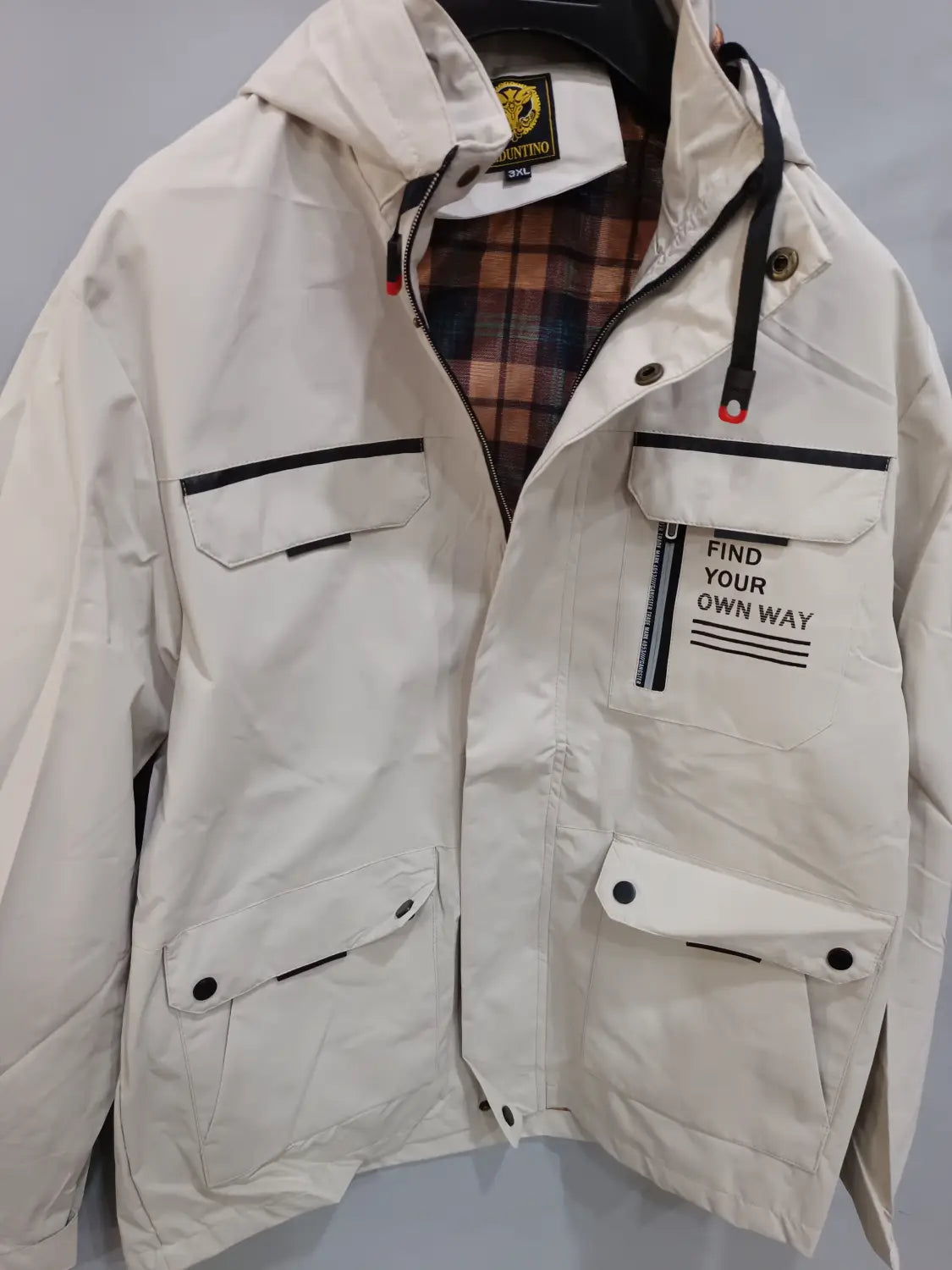 Men winter hooded parka coat in off-white with black trim button-flap pockets and plaid lining.