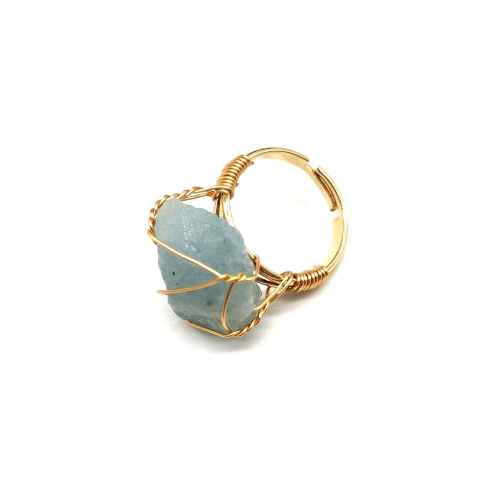 A handcrafted gold wire wrapped adjustable ring featuring a delicate raw light blue gemstone.