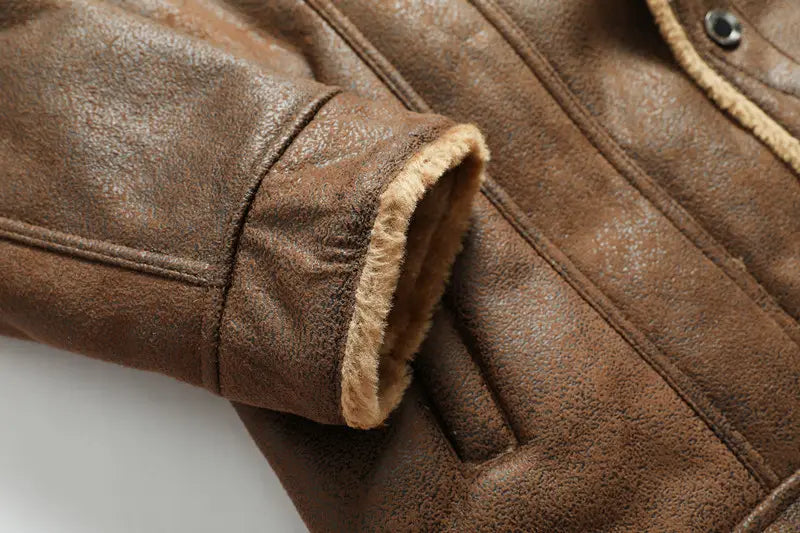 Veste en denim doublée de polaire d’hiver pour homme, en peau de mouton, en cuir marron, avec une doublure beige douce et duveteuse visible au niveau de la manchette.