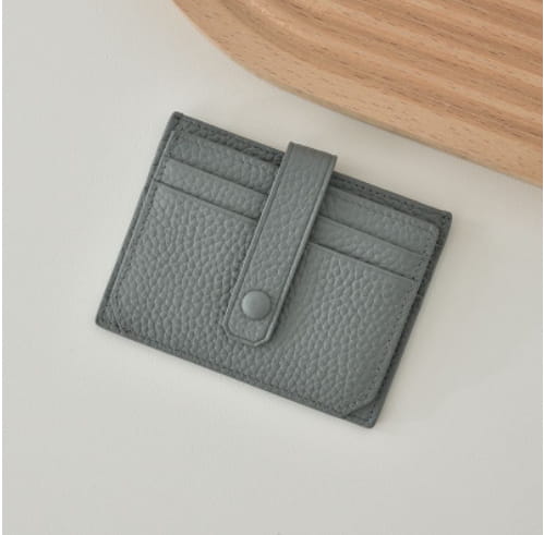 Ultra thin minimalist gray textured leather card holder with flap closure secured by a single button and strap.