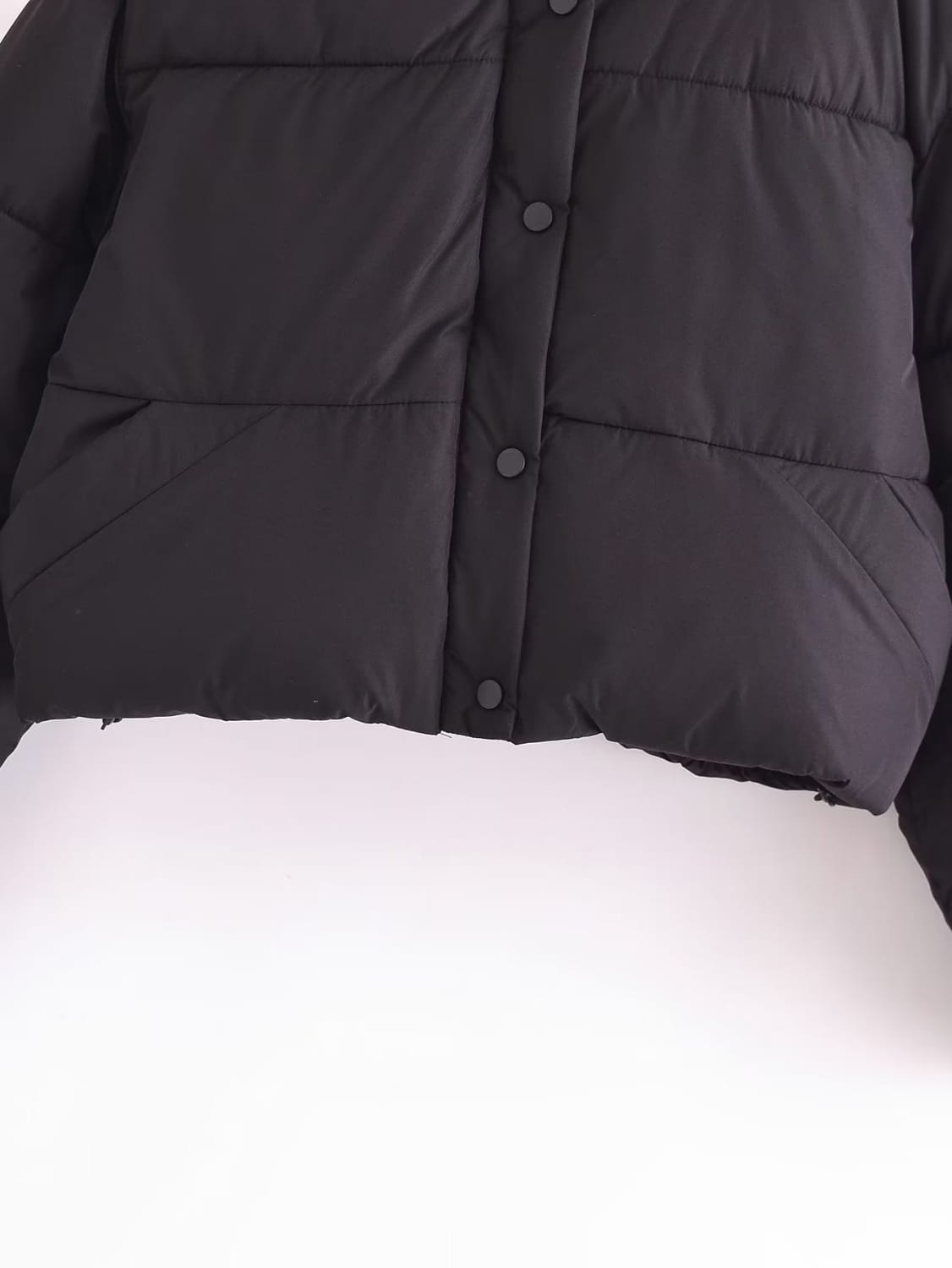 Black quilted hooded puffer coat featuring quilted panels and dark buttons in a black puffer jacket style.