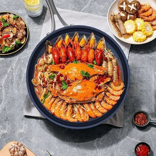 Poêle à frire antiadhésive en titane bleu marine de 10 pouces, remplie d’un assortiment de fruits de mer vibrant, avec acier inoxydable, comprenant de vifs crabes oranges, crevettes, palourdes et moules.