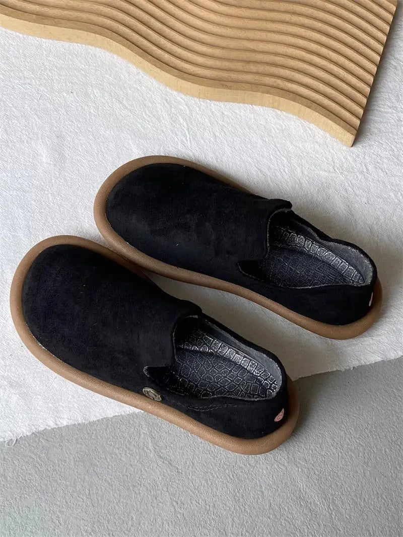 Schwarze Veloursleder-Slipper im Vintage-British-Stil mit niedrigem Absatz mit brauner Gummisohle und dezentem Branding auf der Innensohle.