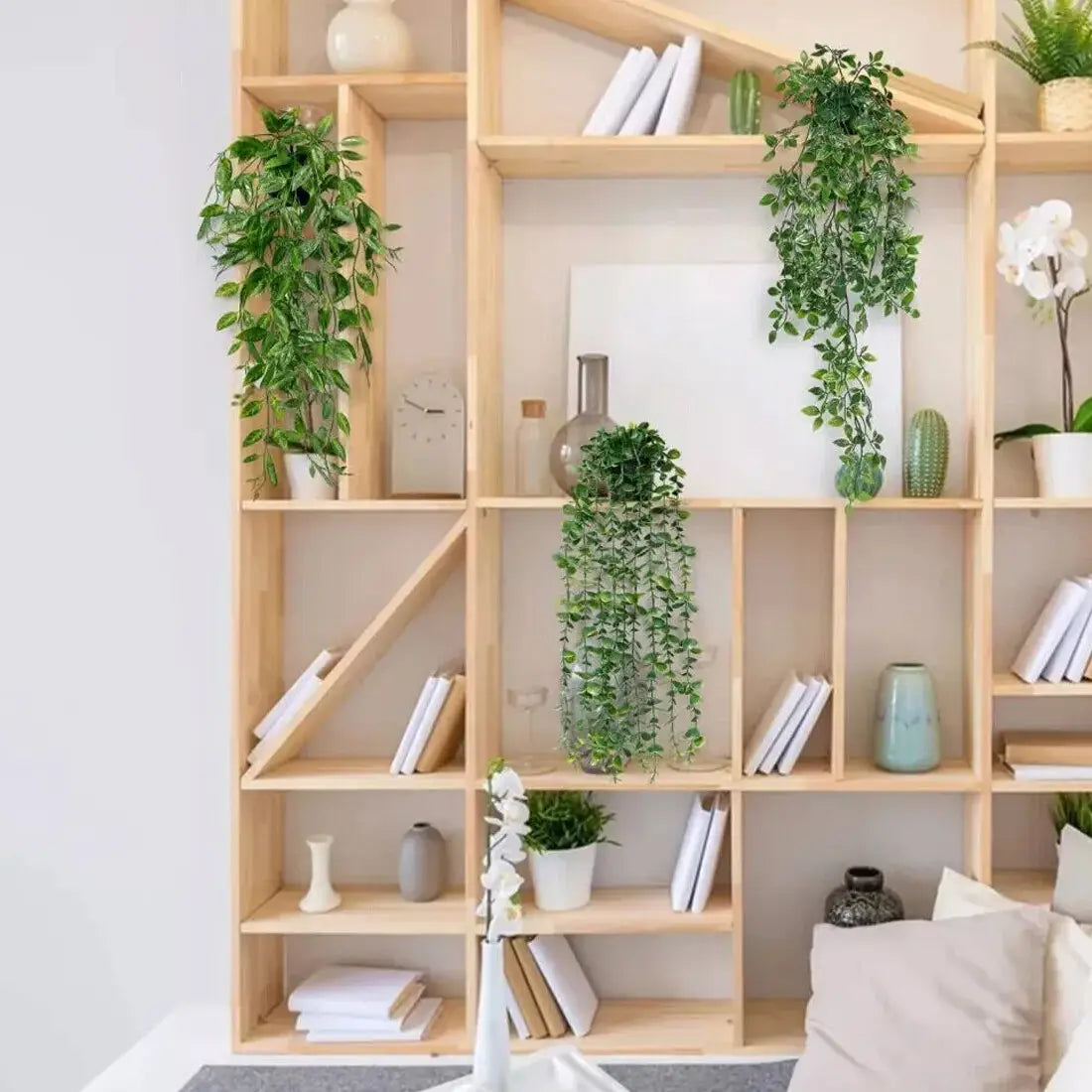 light wood bookshelf with geometric compartments decorated with artificial hanging plants 3 pack fake trailing greenery in vibrant green color