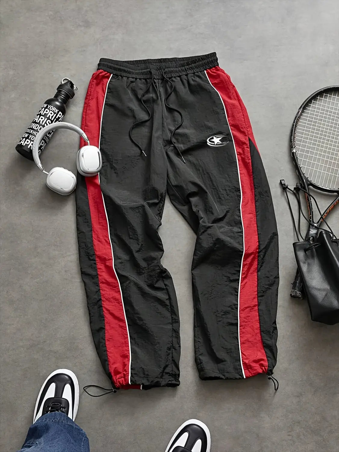 Men quick dry athletic track pants in black featuring bold red side stripes and a small white logo on the left thigh.