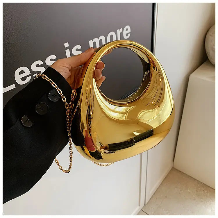 A sleek glossy gold acrylic handbag featuring a rounded handle and metallic chain strap suitable as a clutch bag.