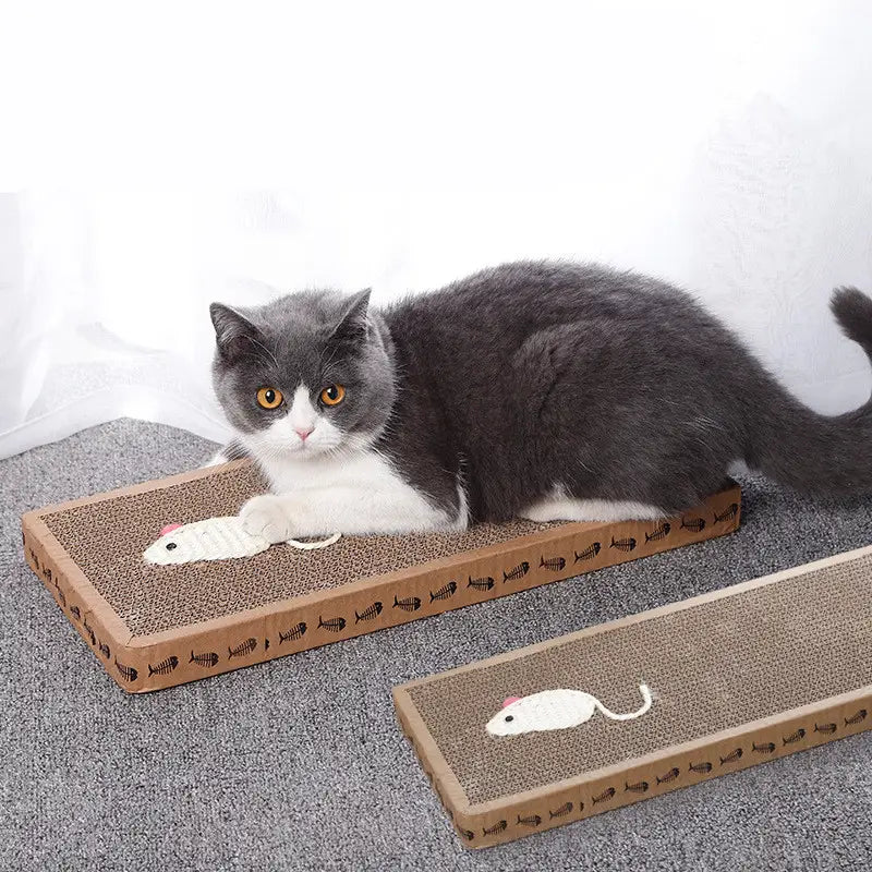 Gato gris y blanco descansando sobre un tablero rascador rectangular de sisal para gatos con una superficie de cartón texturizada y un juguete de ratón de felpa bordado.