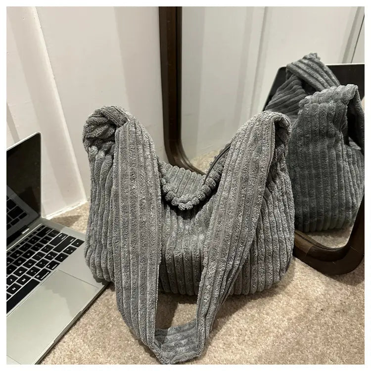 Grau-schattierter Corduroy-Schulterbeutel mit kräftiger gerippter Textur und verdrehten Trägern, ausgelegt für minimalistisches Streetwear.