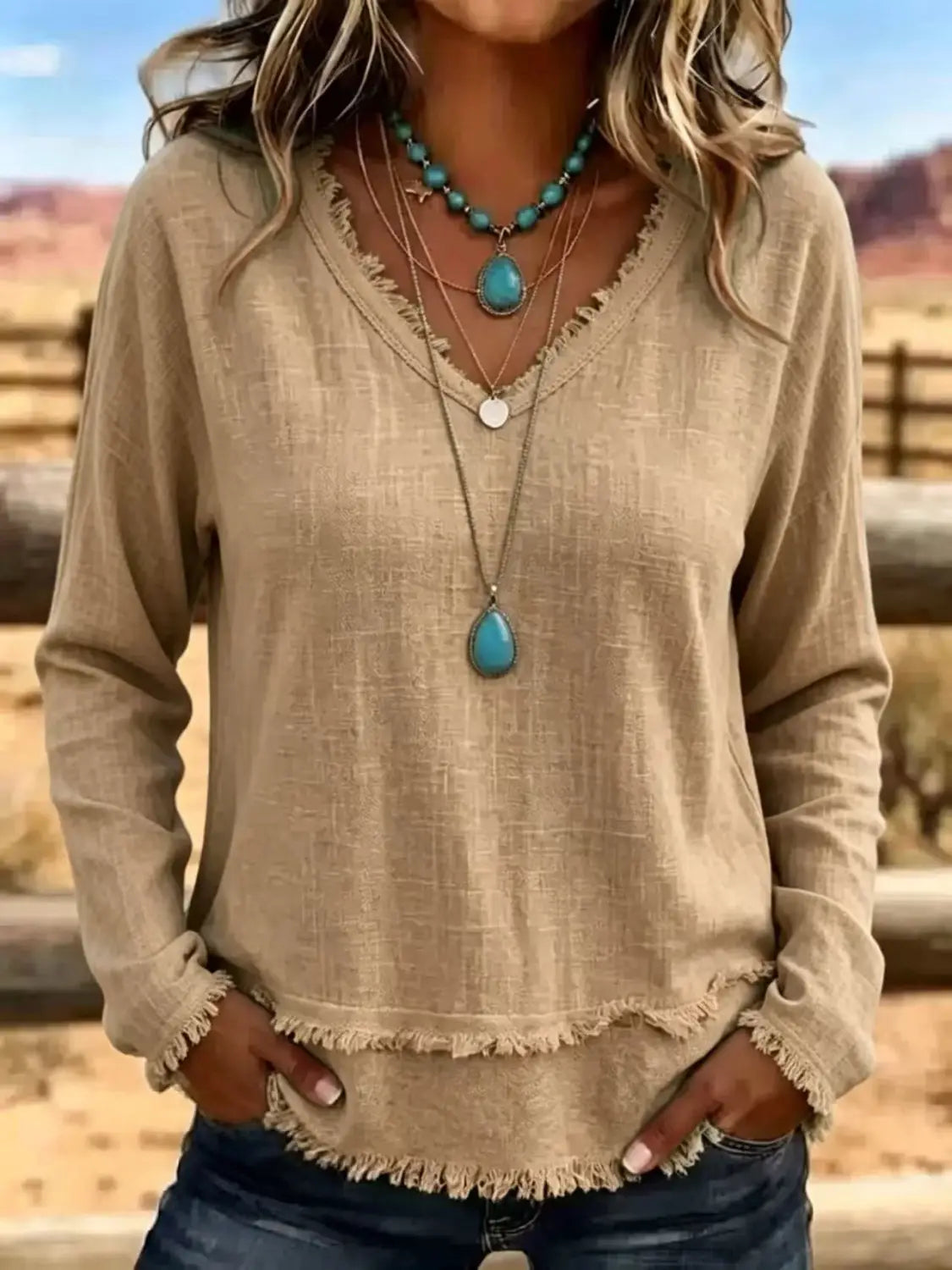 T-shirt pour femmes beige à encolure en V et manches longues, avec ourlet effiloché, conçu comme un haut décontracté.
