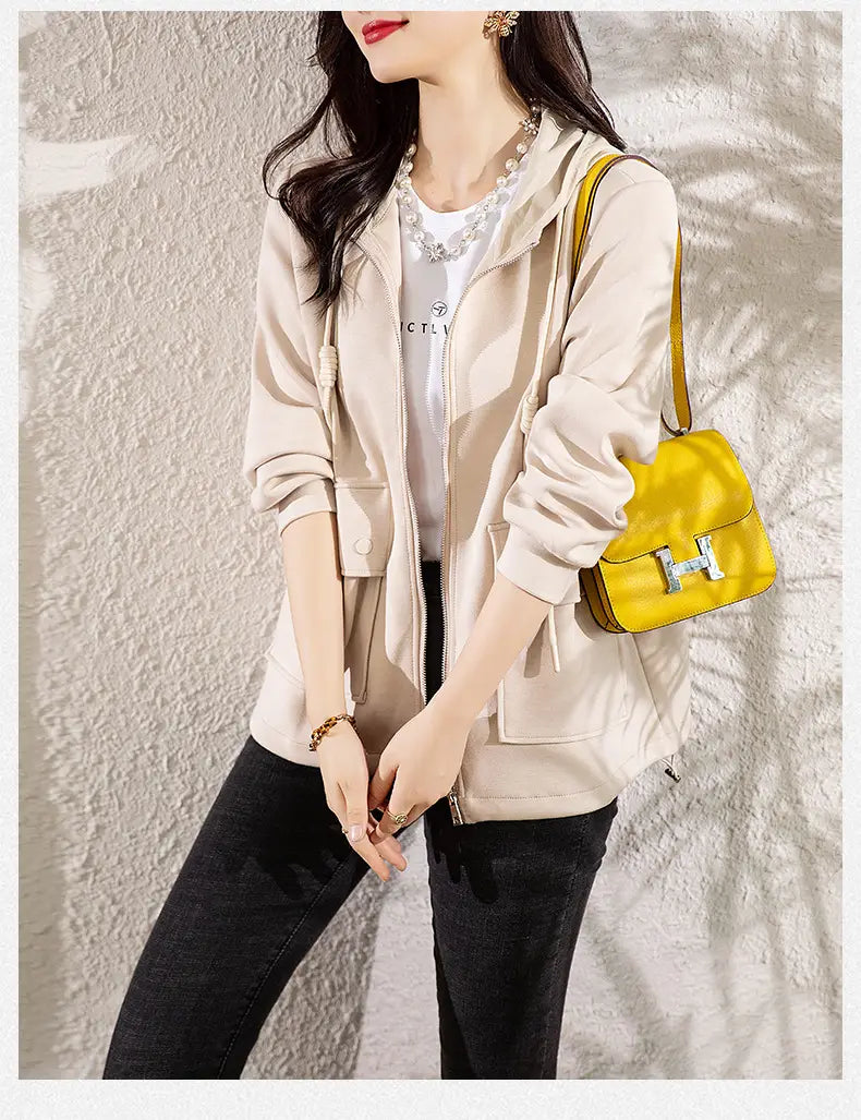 Beige Kapuzen-Cropped-Jacke in Kombination mit einer leuchtend gelben Ledertasche mit silbernem h-förmigen Verschluss.