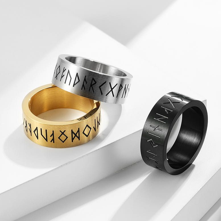Three metallic engraved runic titanium steel band rings for men and women available in silver gold and black finishes.