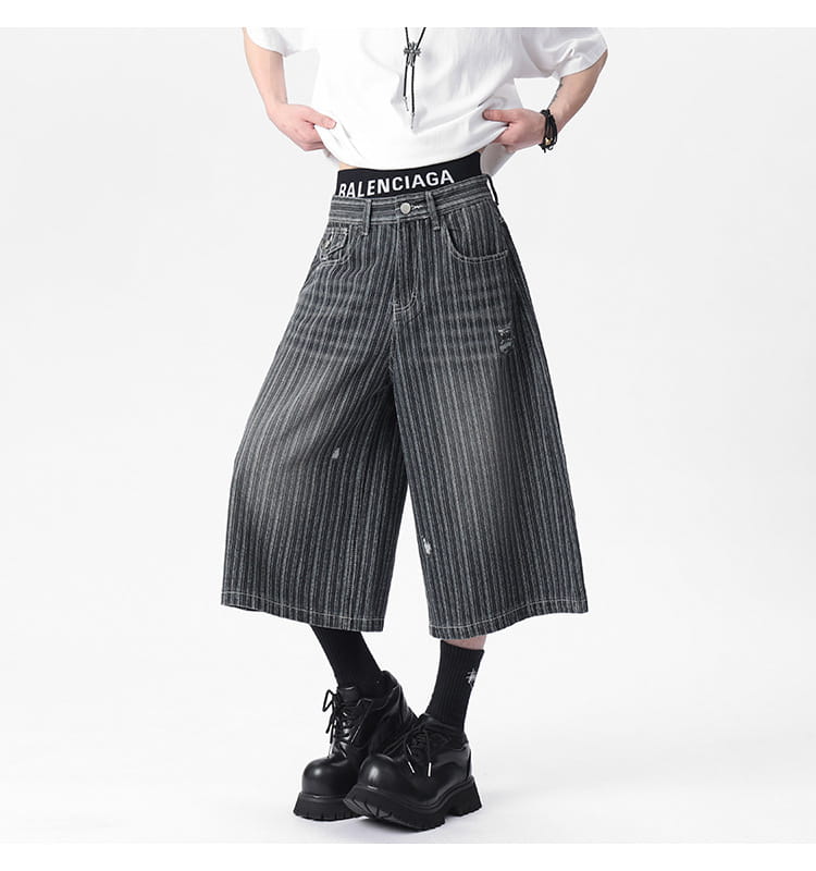 Striped denim capri shorts featuring black and white vertical stripes with distressed ripped detail at the knee and wide-leg design.
