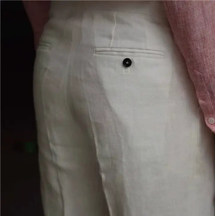 White linen high waisted trousers for men shown from the back with a subtle texture and a single black button on the back pocket.