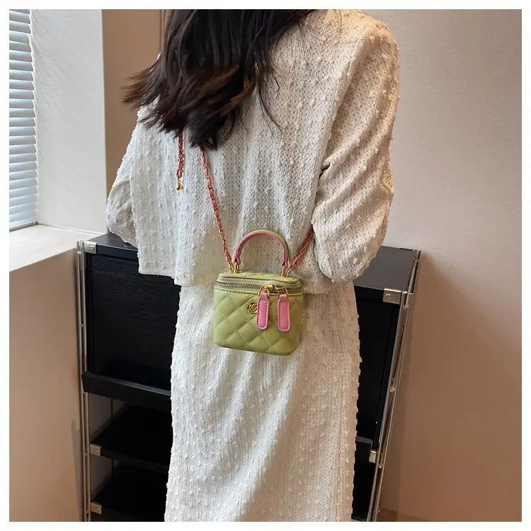 Pastel green quilted diamond mini handbag with pink leather handles and chain strap made of pu leather for crossbody use.