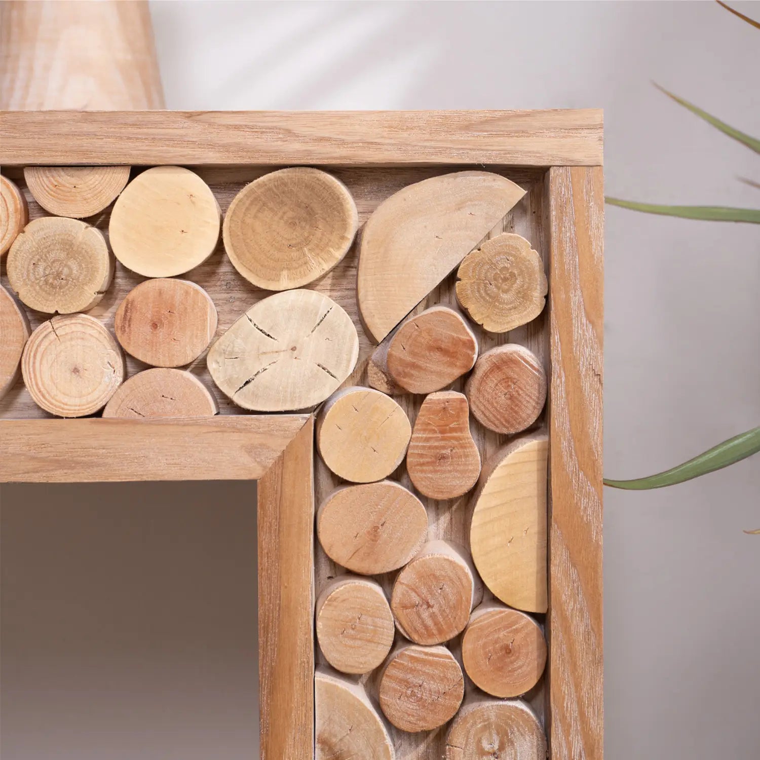 Una mesa consola rústica de madera con acentos de troncos naturales, con un estante de madera que incorpora cortes de madera circulares y semicirculares en diversos tonos marrón claro.