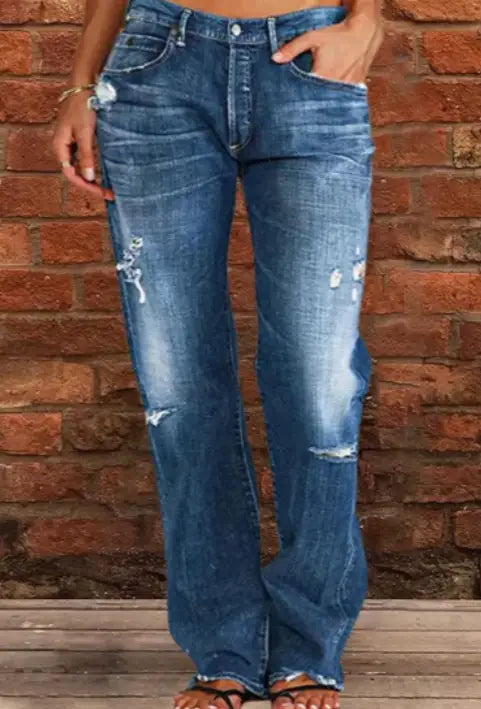 Jeans en denim à jambes droites amples et déchirées, effet vieilli, en denim bleu, avec des déchirures intentionnelles et un délavage.