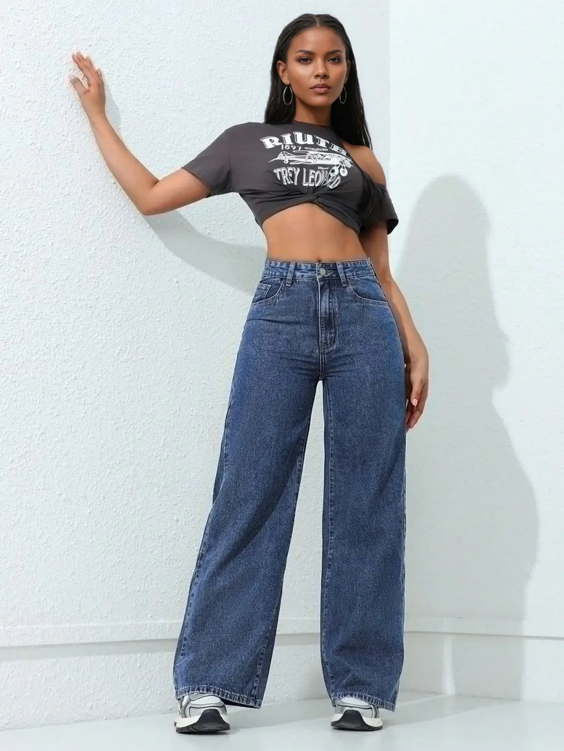 Jean à taille haute, jambe large et évasée, en denim bleu moyen, avec une couture classique et une braguette boutonnée, présenté de face.