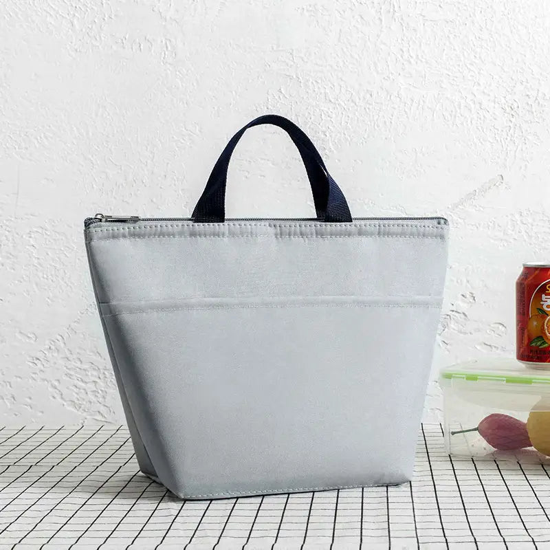 Hellgraue isolierte Oxford-Bento-Lunchbag mit schwarzen Stoffgriffen und Reißverschlussverschluss zur Aufbewahrung und zum Transport von Lebensmitteln.