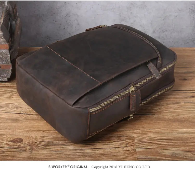 Men’s vintage leather backpack in dark brown cowhide featuring visible stitching and brass zippers.