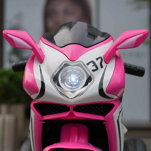 Pink and white 6v kids electric ride on motorcycle with black accents, bright headlight, and the number 37 on the front fairing.