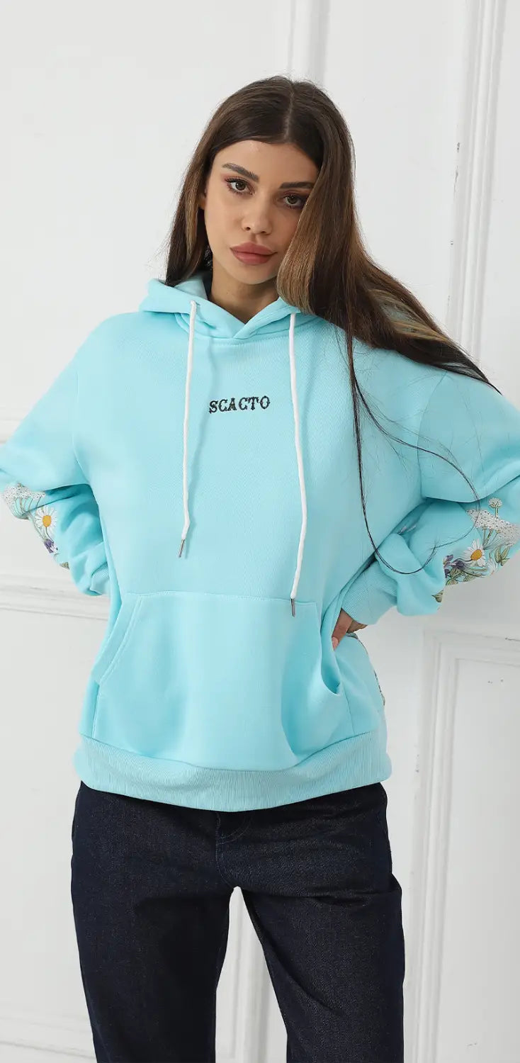 Light blue women’s oversized long sleeve hoodie with floral embroidery on the sleeves white drawstrings and a front pocket.