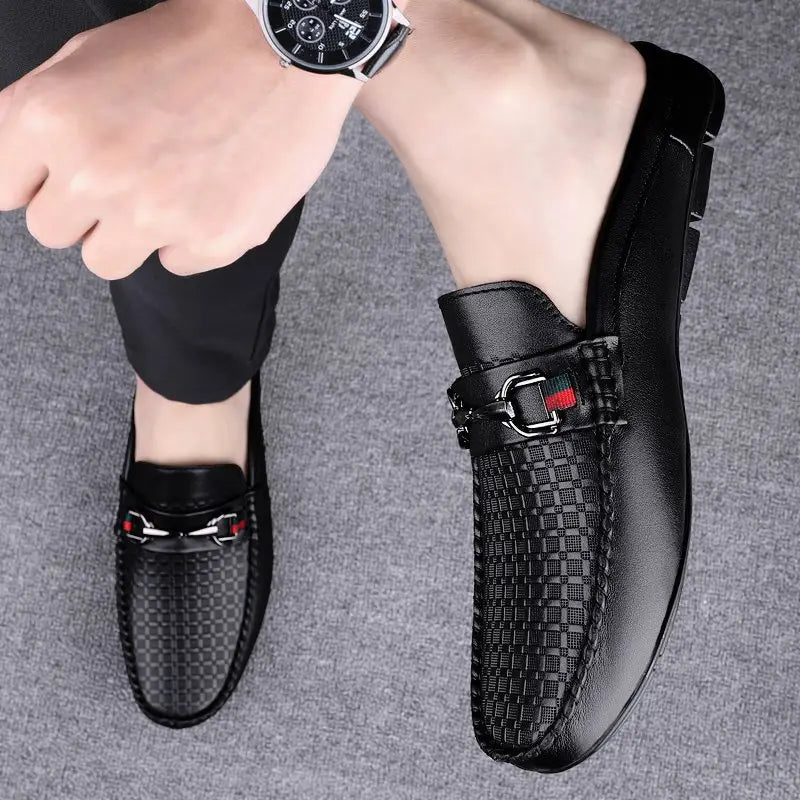 Men’s leather mule loafers in black featuring a woven texture and silver-toned buckle accents with red detailing.