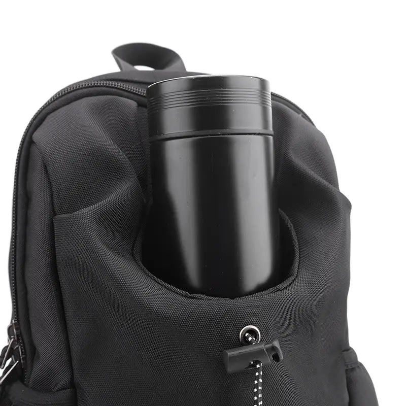 Schwarze zylindrische Edelstahl-Reise-Thermobecher mit einem eleganten gebürsteten Finish und dezenten horizontalen Rillen nahe der Oberkante, dargestellt neben einer wasserdichten Herren-Oxford-Gewebe-Minimalist-Crossbody-Brusttasche.