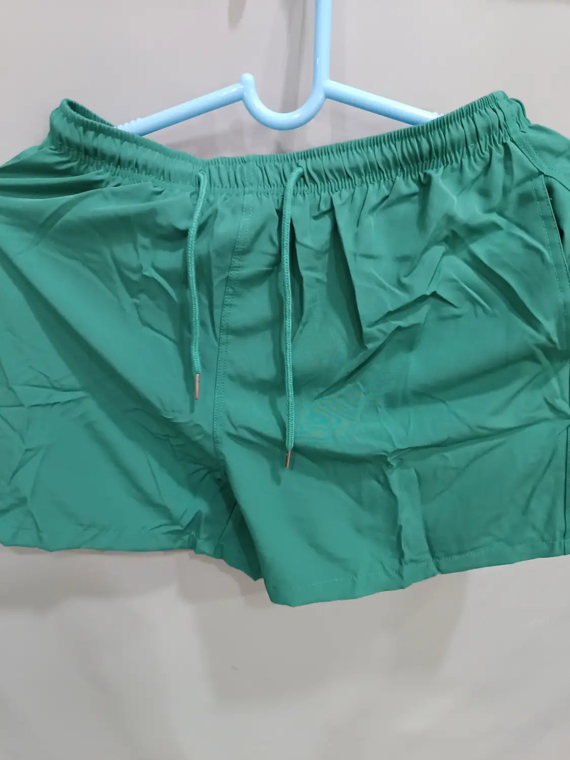 Green printed men beach shorts with elastic waistband and matching drawstring designed as summer swim trunks.