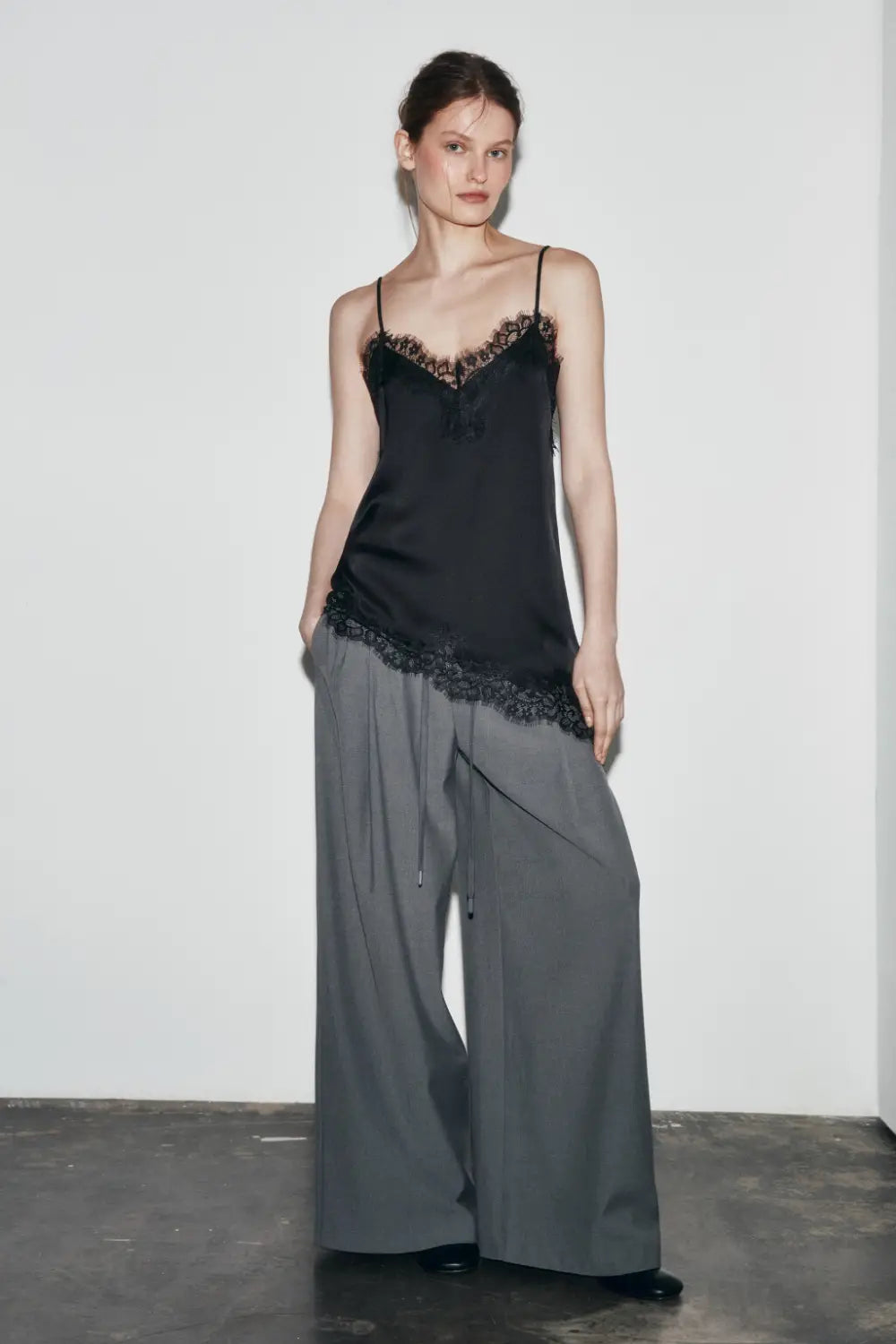 Schwarzes Satin-Camisole-Top mit zartem Spitzenbesatz entlang des Ausschnitts und Saums.