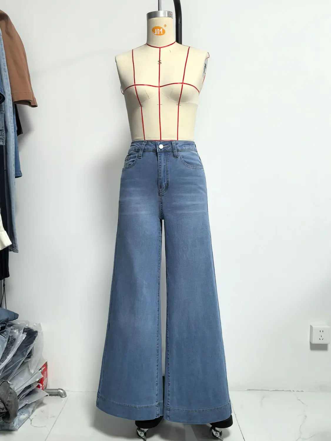 Helle Waschung Blaue Denim-Hochsitz-Wide-Leg-Hosen, an einer Schaufensterpuppe als Teil der Kollektion olivgrüner Denim-Jeans mit weitem Bein dargestellt