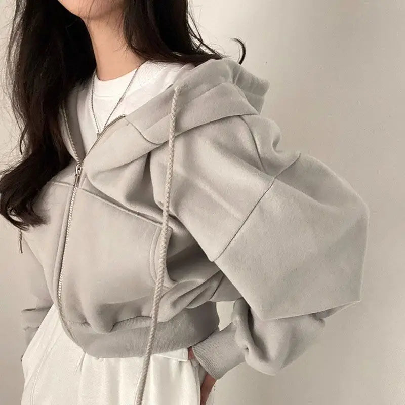 Ein weicher, hellgrauer, verkürzter Hoodie mit gemütlicher Kapuze und gerippten Bündchen, dargestellt neben einem dunkelblauen Samt-Velours, wattierten Kapuzenpullover mit schmaler Passform