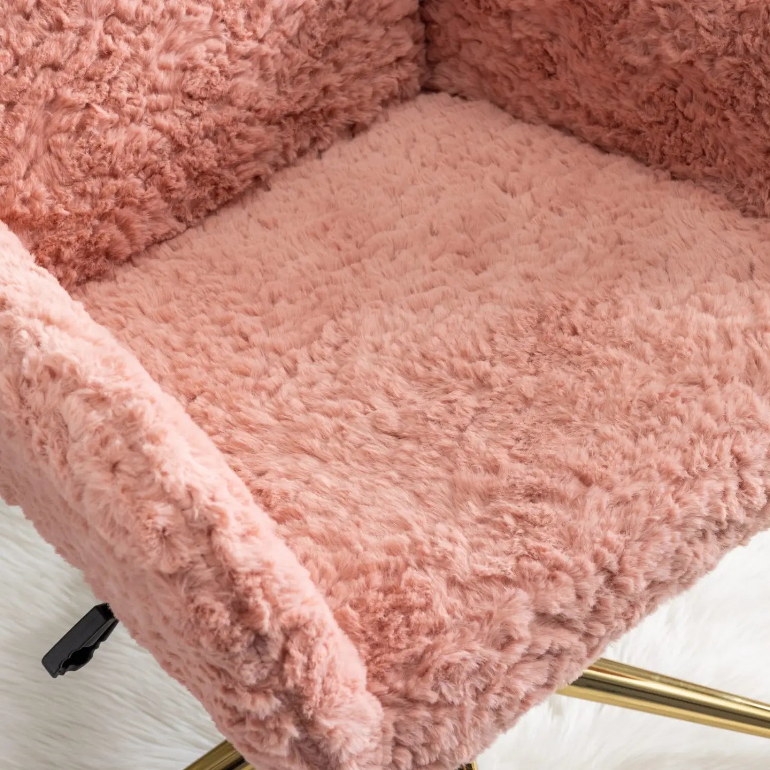 Une chaise de bureau en fausse fourrure rose, présentant une surface texturée et moelleuse ainsi qu’un piétement en métal doré, conçue pour une assise confortable au poste de travail.