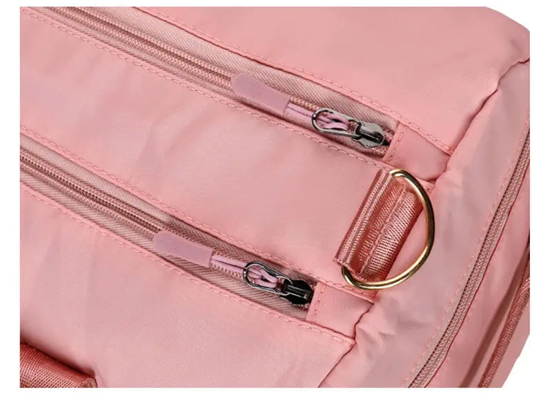 Pink nylon waterproof oxford travel duffel with metallic zippers and a gold-toned d-ring designed for gym and sports use.
