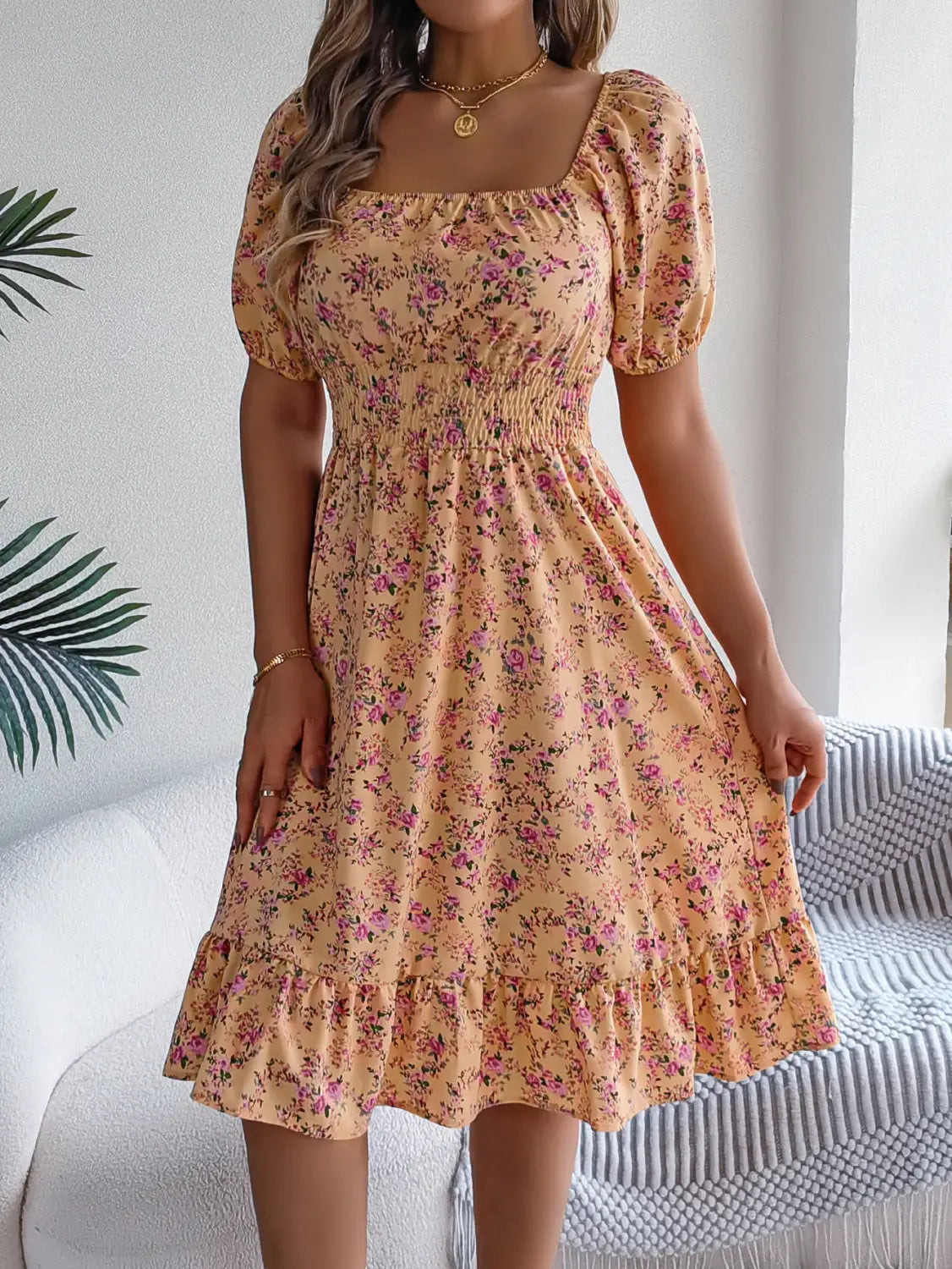 Robe d’été florale couleur pêche, avec manches courtes bouffantes, encolure carrée et ourlet à volants.