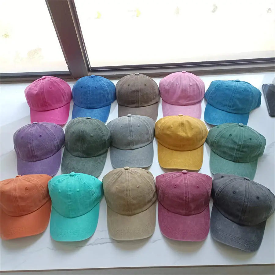 A collection of colorful cotton baseball caps in vintage washed texture featuring soft hues of pink blue green yellow and orange designed as sun hats.