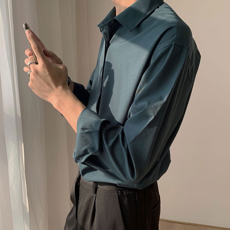 A sleek dark teal long-sleeved wrinkle resistant satin button down shirt with a subtle sheen and classic collar.