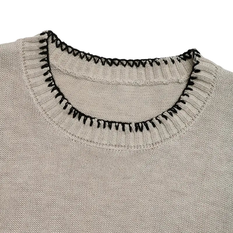 Haut sans manches en maille beige avec encolure côtelée et passepoil contrastant noir à motif zigzag, réalisé en tissu tricoté.