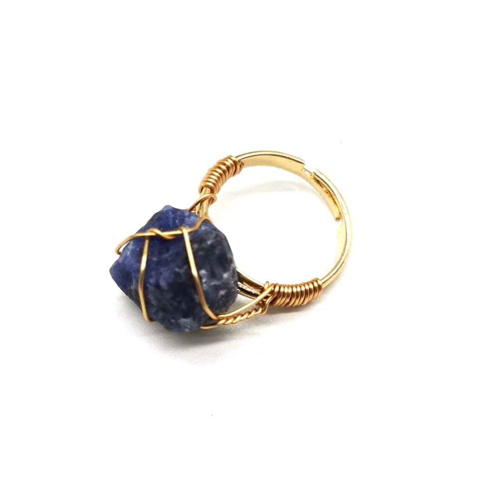 A handcrafted gold wire wrapped adjustable ring featuring a raw deep blue sapphire gemstone.
