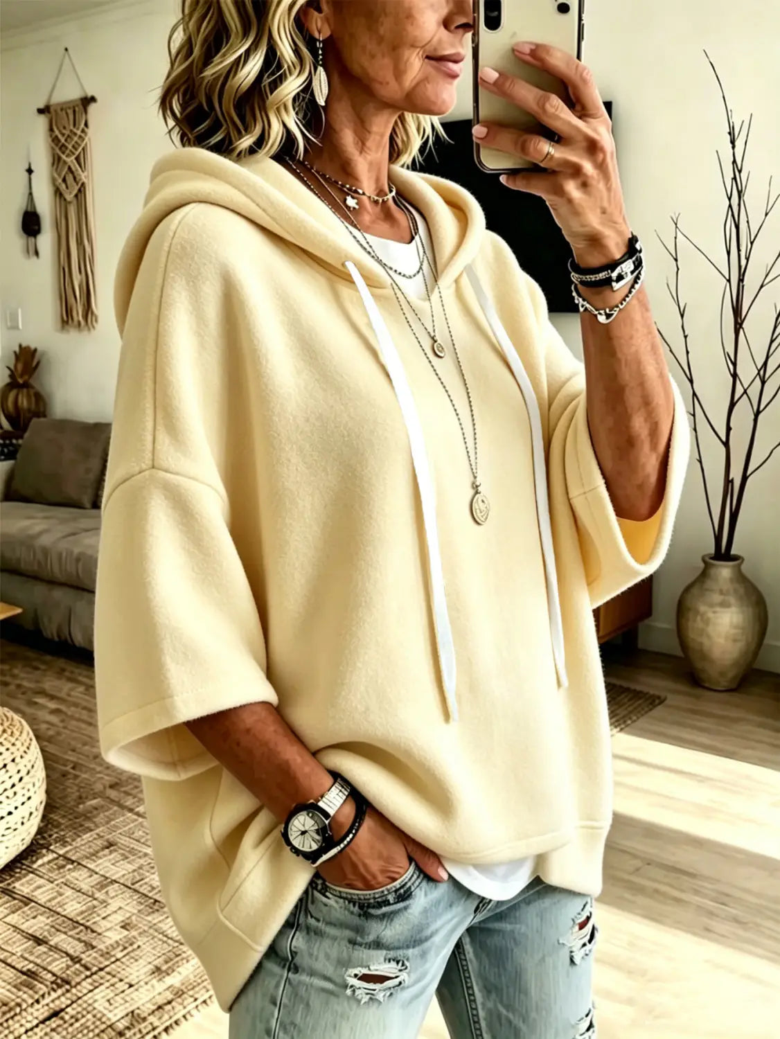 Cream-colored oversized fleece hooded top with three-quarter sleeves white drawstrings and a relaxed fit.