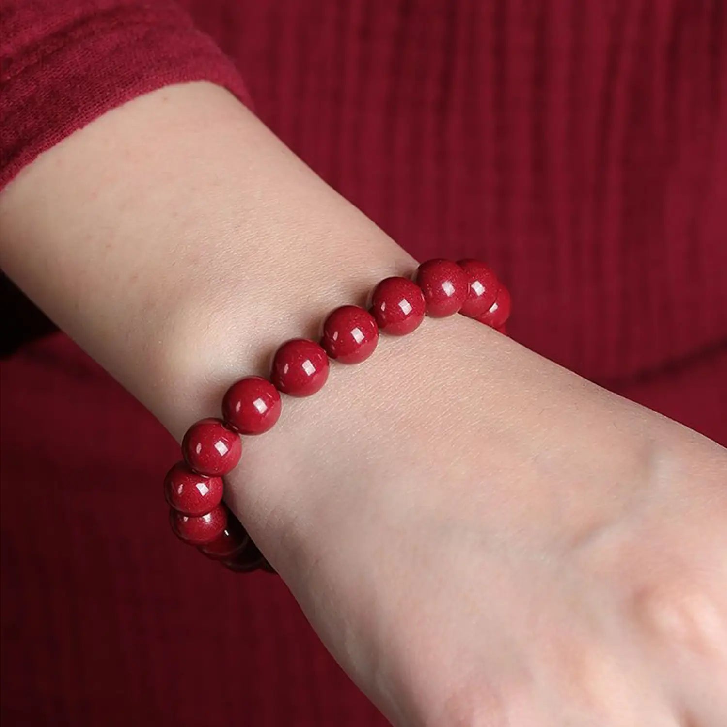 a polished red cinnabar spherical bead bracelet with a vibrant glossy finish worn on a wrist