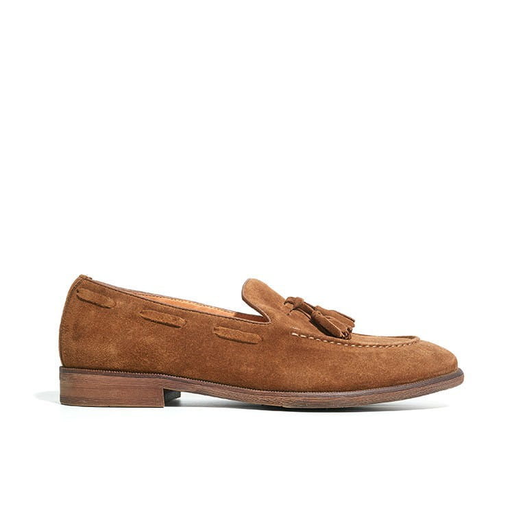 Mocassin à pampilles en daim beige avec des coutures cousues et une semelle en caoutchouc cousue visible sur le côté.