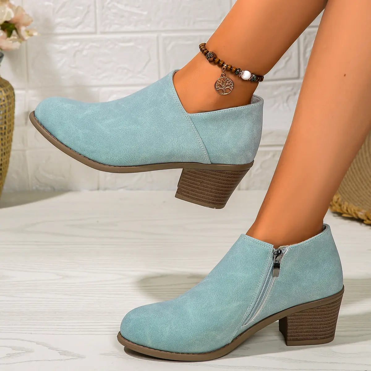 Light blue suede ankle boots with a chunky stacked brown heel and side zipper closure.